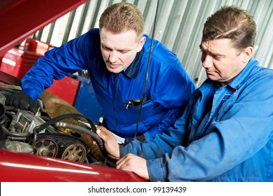 two motor mechanic engineers examining timing belt and internal combustion engine of automobile car at repair service station