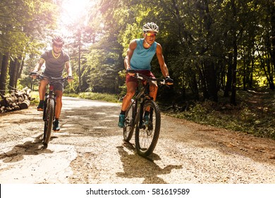 Two mountain bikers riding bike in the forest on dirt road. - Shutterstock ID 581619589