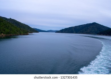 Two Mountains With Boat Wake In The Background