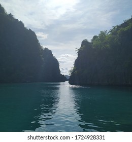Two mountains facing each other are situated in a lake, showing shaded and lit areas.