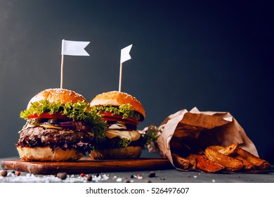 Two mouth-watering, delicious homemade burger used to chop beef. on the wooden table. small white flags inserted in the burgers. - Powered by Shutterstock