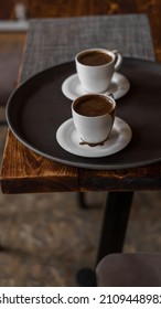 Two Mugs Of Coffee Stands On A Tray In A Restaurant.  Dark Colors, Loft Style Interior.  No People