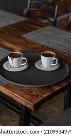 Two Mugs Of Coffee Stands On A Tray In A Restaurant.  Dark Colors, Loft Style Interior.  No People