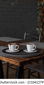 Two Mugs Of Coffee Stands On A Tray In A Restaurant.  Dark Colors, Loft Style Interior.  No People