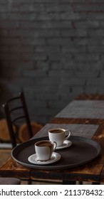 Two Mugs Of Coffee Stands On A Tray In A Restaurant.  Dark Colors, Loft Style Interior.  No People