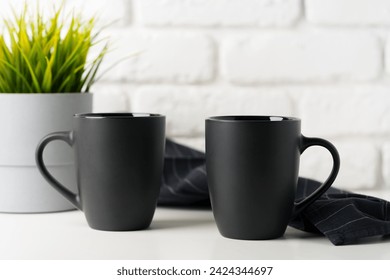 Two mugs on white table against brick wall background