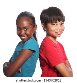 Two multi racial school kids standing back to back, boy and girl wearing blue and red t-shirts against white background, showing happy smiles from pair of friends.