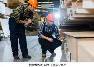 two multicultural colleagues in uniform and helmets working in warehouse