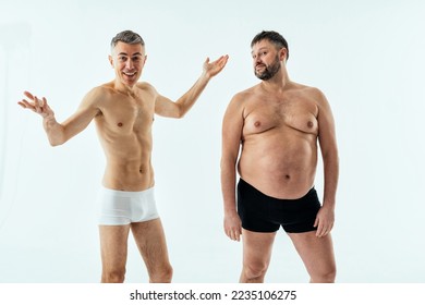 Two multiethnic men posing for a male edition body positive beauty set. Shirtless guys with different age, and body wearing boxers underwear