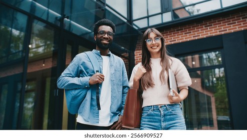Two multi-ethnic programmers talking with each other under company building. Asking questions about work or plans for evening. People communicating in free time. Getting to know colleagues.