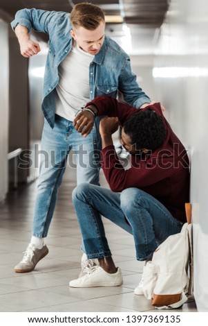 two multiethnic students fighting in corridor in college