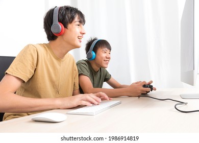 Two Multiethnic Teenage Boys Playing Online Computer Games At Home.