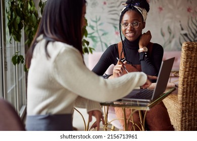 Two Multiracial Female Students Sit In A Bar And Read A Book. Students Study For An Exam.