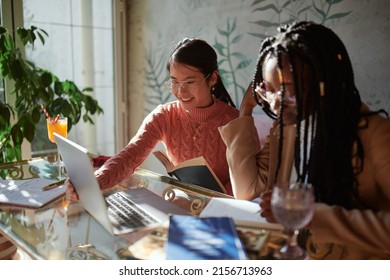 Two Multiracial Female Students Sit In A Bar And Read A Book. Students Study For An Exam.