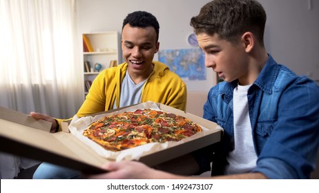 Two multiracial friends opening box with pizza for student party, food delivery - Powered by Shutterstock