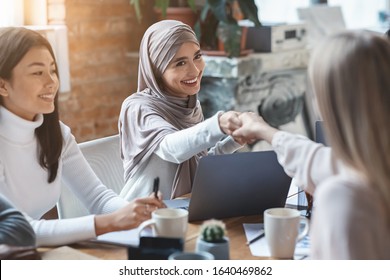 Two multiracial girls business colleagues shaking hands during group meeting in office, close up