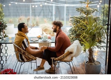 Two multiracial male friends having close conversation, sitting by a dinner table on a beautiful house terrace outdoors. Caucasian and hispanic man together at backyard - Powered by Shutterstock