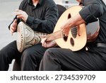 Two musicians performing Middle Eastern music with a wooden oud and an ornate percussion instrument, sharing cultural heritage
