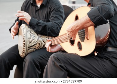 Two musicians performing Middle Eastern music with a wooden oud and an ornate percussion instrument, sharing cultural heritage