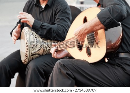 Two musicians performing Middle Eastern music with a wooden oud and an ornate percussion instrument, sharing cultural heritage
