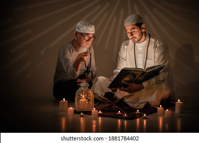 Two Muslim People Read And Study Islam Holy Al Quran Book Together During Ramadan Period. Al Quran Book With Written Arabic Calligraphy Meaning Of Al Quran