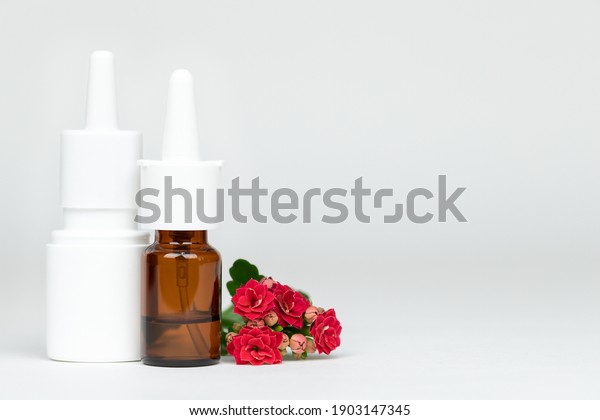 Two nasal spray bottles of medicine with flowers
on light background,
allergy