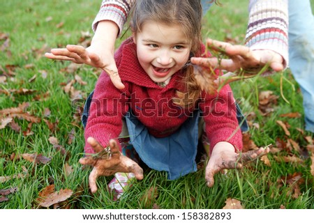 Two Naughty Sisters Young Girls Playing With Muddy Hands In A Park With Green Grass And Two Naughty Sisters Young Girls Playing With Muddy Hands In A Park With Green Grass And