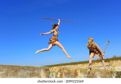 Two neanderthal women are on the attack. They 
are seen on large boulders. One girl leaps in 
mid-air and screams out loud to her companion.