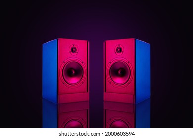 Two neon colored stereo speakers on dark background with reflection.Sound audio loud speakers, close up