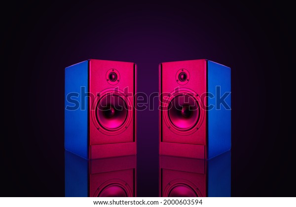 Two neon\
colored stereo speakers on dark background with reflection.Sound\
audio loud speakers, close\
up