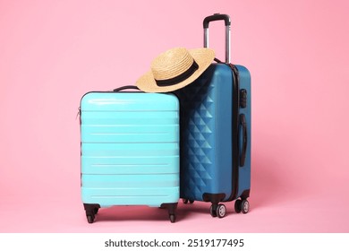 Two new color suitcases and wicker hat on pink background