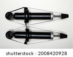 Two new shock absorbers for the car on a flat surface. A set of spare parts for the repair of the chassis of the vehicle. Details on white background, copy space available. UHD 4K.