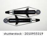 Two new shock absorbers for the car lie on a flat surface. A set of spare parts for the repair of the chassis of the vehicle. Details on white background, copy space available. 