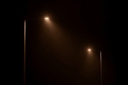 Deux Lampadaires De Nuit Brille D'une Lumière Jaune Mystérieuse à Travers Le Brouillard Du Soir. Les Lumières Des Rues Brillent La Nuit Tranquille De La Ville, La Lumière Atmosphérique Magique Dans L'obscurité Mystique