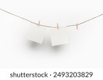 two note paper cards hanging with wooden clip or clothespin on rope string peg isolated on white background.