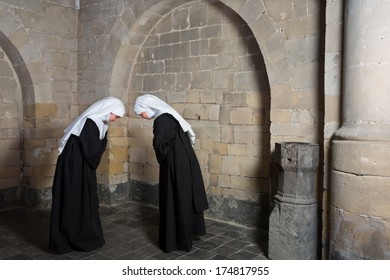 Two Nuns Greeting Eachother Inside A Medieval Abbey