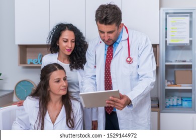 Two nurses, female physicians, and a male doctor looking in a tablet at the doctor's office while discussing a medical report ( patient's health problems ). - Powered by Shutterstock