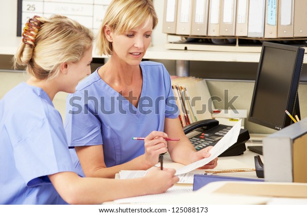 Two Nurses Working At\
Nurses Station
