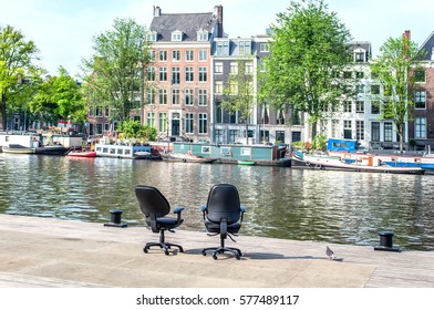 Two Office Chairs Opposite The Buildings In Amsterdam, Netherlands