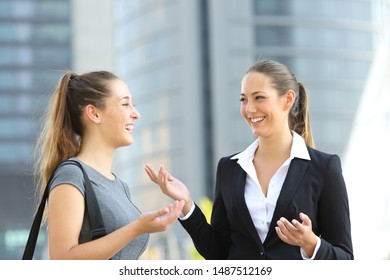 Two Office Employees Talking Standing In The Street With Office Buildings In The Background