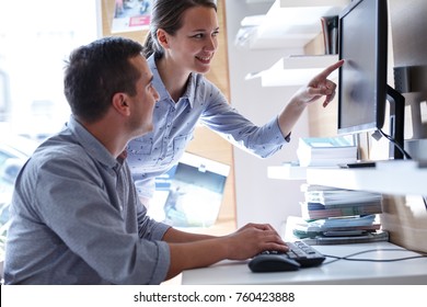 Two office workers sitting in office ad using computer.They working on new project.