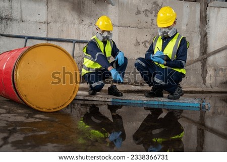 Two officers wearing gas masks inspected the area of a chemical leak in an industrial warehouse to assess the damage. Technicians wearing gas masks inspect and assess the recovery of toxic spills. 商業照片 © 