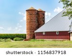 Two old brick silos stand next to a refurbished old barn. Summer farm scene with unique, handmade, hundred year old brick silos.  Concepts of agriculture, farming, history