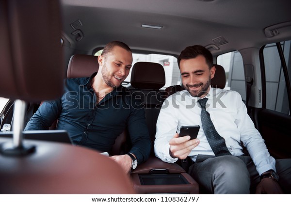 The two old business\
friends conclude a new agreement in an informal setting in the\
car\'s interior.