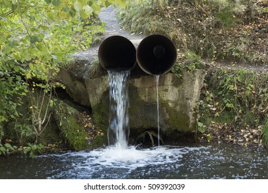 Two Old Drain Water Tubes With Running Stream Of Water Flowing Out Of One And Trickle Of Water Flowing Out Another One