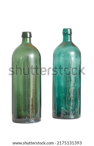 Two old empty glass bottles isolated against a white studio background with copyspace. Colourful antique glassware used as decorative art piece. Transparent vintage containers to recycle or repurpose