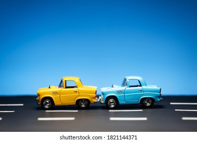 Two Old Fifties Toy Model Cars One Yellow And One Blue  Stand In A Row On A Road And A Blue Background.