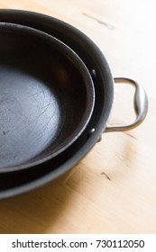 Two old frying pans stacked together on a wooden background.