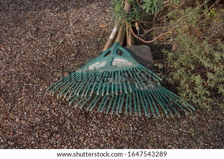 Two Old Green Plastic Garden Rakes Lying on a Gravel Path in a Park in Rural Devon, England, UK