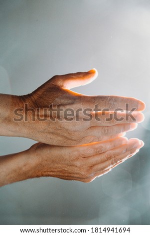 Two old hands asking for something while the light reflects in the hands